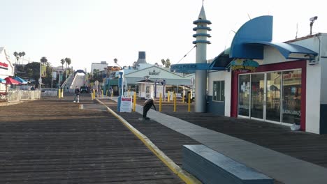 Schwenkaufnahme-Von-Menschen,-Die-Nach-Der-Wiedereröffnung-Aufgrund-Von-Covid-19-Am-Eingang-Des-Santa-Monica-Pier-In-Los-Angeles-Entlanglaufen