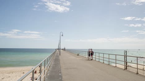 Families-and-friends-enjoying-walk-along-jetty,-Time-lapse-slow-zoom-in