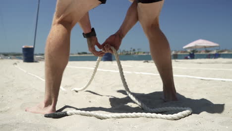 El-Atleta-Masculino-Se-Prepara-Para-Tirar-Pesas-Rusas-Con-Cuerda-Durante-La-Competencia-De-Fitness-En-La-Playa---Anticipación