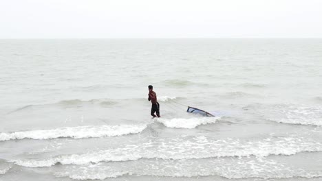 Man-walking-in-shallow-water,-dragging-a-traditional-fishing-net-in-the-Indian-Ocean