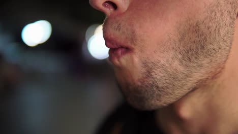 Extreme-Close-Upshot,-Man-eats-a-barbeque-baby-Squid,-Blurred-lights-in-the-background