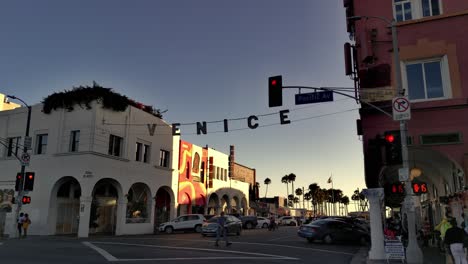 Venice-sign-panning-shot-at-corner-of-Pacific-Ave---Windward-Ave-with-traffic-,-during-sunset,-in-Los-Angeles,-California,-USA