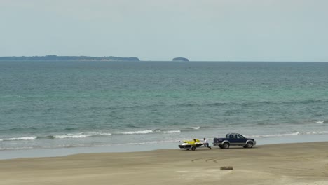 Man-unloading-jet-ski-into-ocean-on-his-own