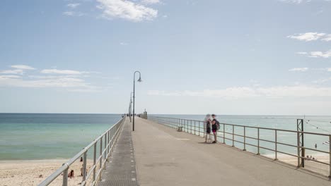 Zeitraffer-Von-Touristen,-Die-Mittags-Am-Steg-Von-Glenelg-Entlanggehen,-Heranzoomen