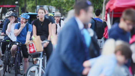 Multitud-Anónima-Cruzando-La-Calle-Frente-A-Ciclistas-Esperando-Su-Turno,-Cámara-Lenta