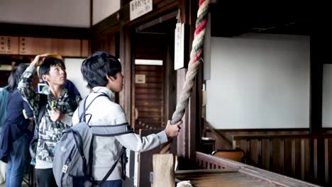 Niño-Japonés-Tocando-La-Campana-En-El-Templo-Y-Rezando---Kyoto