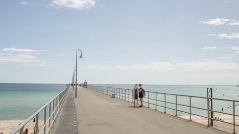 Time-lapse-of-people-walking-along-Glenelg-Jetty,-pan-right