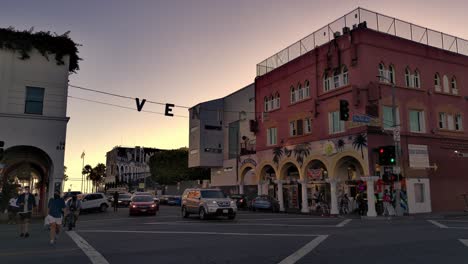 Venice-sign-panning-shot-at-the-corner-of-Pacific-Ave---Windward-Ave-with-traffic,-in-the-evening-during-sunset,-in-Los-Angeles,-California,-USA