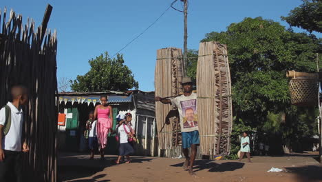 Male-Malagasy-Carrying-Heavy-Load-On-Shoulders-With-Bamboo-Pole-In-Farafagana