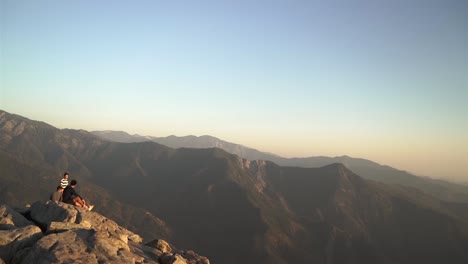 Cinematic-aerial-shot-of-tourists-enjoying-the-sunset-at-Moro-Rock-in-California's-Sequoia-National-Forest