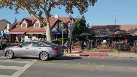 Coches,-Un-Viejo-Molino-De-Viento-Y-Gente-En-Un-Restaurante,-En-El-Pueblo-De-Solvang,-California,-EE.UU.,-Día-Soleado---Vista-Panorámica