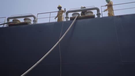 Männliche-Besatzungen-Auf-Dem-Schiffsdeck-Geben-Den-Hafenarbeitern-Im-Hafen-Das-Festmacherseil-Eines-Riesigen-Schiffes-Frei