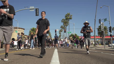 Low-angle,-front-facing-perspective-of-protesters-marching-down-Southern-California-street