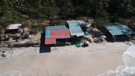 Aerial-Pedestal-Up-View-From-Huts-On-Secret-Beach-At-Padangbai-To-Reveal-Waves-Hitting-Beach,-Bali,-Indonesia