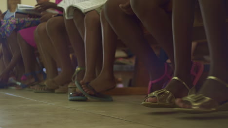 Namibian-school-Kids-seated-restless-playful-in-their-chairs,-Africa---Ground-level-Detail-shot