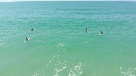 Beginner-group-of-surfers-waiting-for-the-waves-to-form,-on-the-coast-beach-of-Santinho-in-Brazil