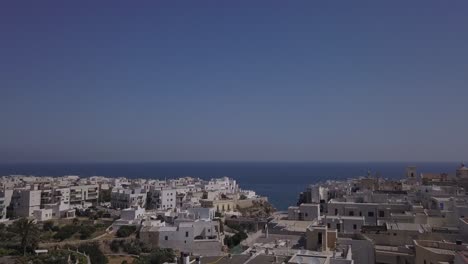 Drone-View-of-Polignano-a-Mare,-shot-going-from-the-town-towards-the-sea,-where-the-red-bull-cliff-diving-takes-place-every-year