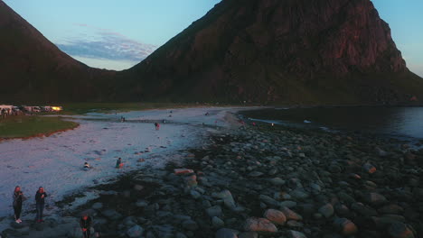 Menschen-Am-Strand-Von-Uttakleiv,-Norwegen,-Genießen-Es,-Die-Mitternachtssonne-Zu-Beobachten,-Eine-Aufnahme-Aus-Der-Tiefsicht