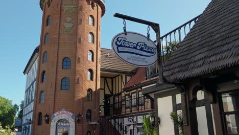 People-eating-at-the-Tower-pizza-restaurant,-sunny-day,-in-Solvang,-California,-USA---Tilt-Up-Shot