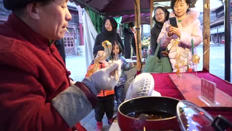 El-Hombre-Hace-Dulces-Animales-Soplando-Como-Vidrio-En-Una-Pequeña-Feria-En-Gubei-Water-Town-Mientras-Los-Niños-Esperan-Que-Comiencen-Las-Celebraciones-Del-Año-Nuevo-Chino.