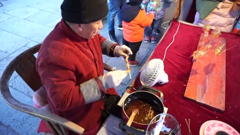 Man-making-candy-animals-by-blowing-in-them-as-glass-blowing-in-a-small-fair-in-Gubei-Water-Town-for-Chinese-New-Year-Celebrations