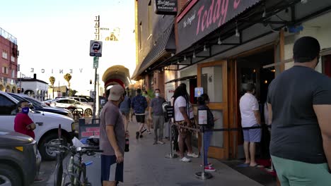 Venice-Beach-masked-people-waiting-in-line-for-food,-at-a-restaurant,-sunny-day,-in-Los-Angeles,-California,-USA---Static-shot