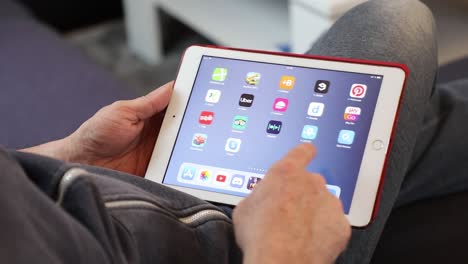 Mitte-Erwachsener-Mann,-Der-In-Ungezwungener-Häuslicher-Umgebung-Durch-Seiten-Mit-Apps-Auf-Einem-IPad-Blättert