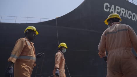 Indische-Hafenarbeiter-Im-Hafen-Mit-Frachtschiff,-Das-An-Einem-Sonnigen-Tag-Festmacht