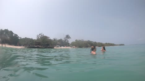 A-mother-and-a-daughter-swimming-in-a-turquoise,-clear-and-transparent-ocean-beach-of-a-paradisiac-island-close-to-Cartagena-de-Indias,-Colombia