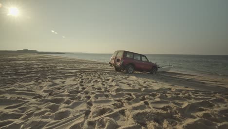 SUV-Rojo-Empujando-Un-Barco-A-Través-De-La-Playa-De-Arena-Hasta-El-Océano-En-Omán