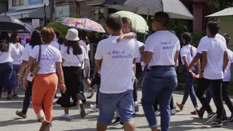 Groups-of-people-parade-in-the-street-during-a-local-churches-annual-celebrations-in-Surigao-City,-Philippines