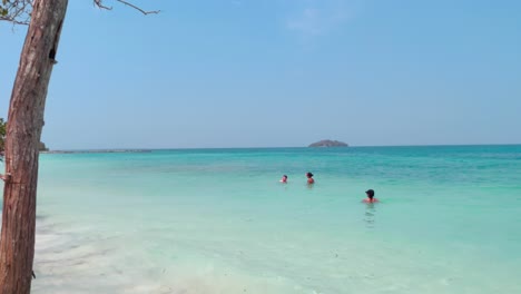 Men-and-women-are-swimming-on-a-turquoise,-clear-and-transparent-ocean-water-of-a-paradisiac-island-near-Cartagena-de-Indias,-Colombia