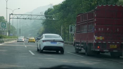 Vista-Desde-El-Parabrisas-Que-Muestra-La-Concurrida-Autopista-De-Beijing-Con-Verdes-Colinas-Forestales-Al-Fondo