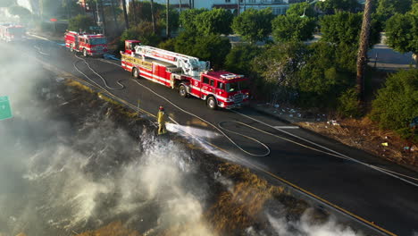 Vista-Aérea-De-Un-Bombero-Del-LAFD-Extinguiendo-Un-Incendio-En-Un-Parque,-En-Los-Ángeles,-Estados-Unidos