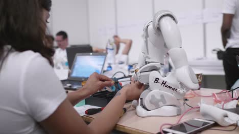 Adult-Female-Engineer-Fixing-Nao-Robot-On-Table