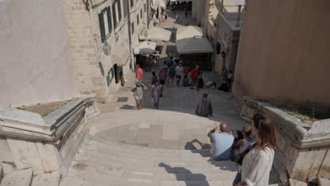 Escaleras-De-Jesuitas-Y-Calles-Estrechas-Con-Muchos-Turistas-Y-Pájaros-Volando,-Cámara-Inclinada-Hacia-Arriba