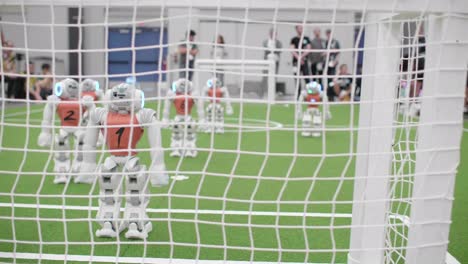 Verfolgen-Sie-Den-Schuss-Hinter-Dem-Fußballtornetz-Mit-Nao-Fußballrobotern,-Die-Auf-Dem-Spielfeld-Stehen