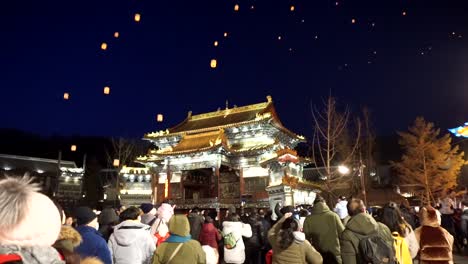 Celebración-Del-Nuevo-Año-Chino-2020-De-Gubei-Water-Town,-Gente-Mirando-Hacia-El-Cielo-Mientras-Linternas-Artificiales-Tradicionales-Son-Levantadas-Por-Drones