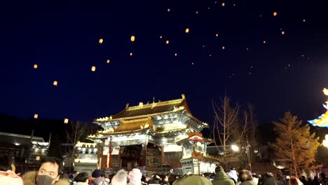 Celebración-Del-Nuevo-Año-Chino-2020-De-Gubei-Water-Town,-Gente-Mirando-Hacia-El-Cielo-Mientras-Linternas-Artificiales-Tradicionales-Son-Levantadas-Por-Drones