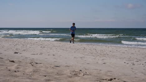 Ein-Junger-Erwachsener-Joggt-An-Einem-Wunderschönen-Herbsttag-In-Litauen-Am-Sandstrand-Der-Ostsee