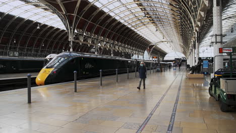 One-person-walking-wearing-face-mask-covering-in-Paddington-Train-Station-during-Coronavirus-Covid-19-lockdown-in-London-when-public-transport-was-quiet-and-deserted-with-no-people-in-England,-Europe