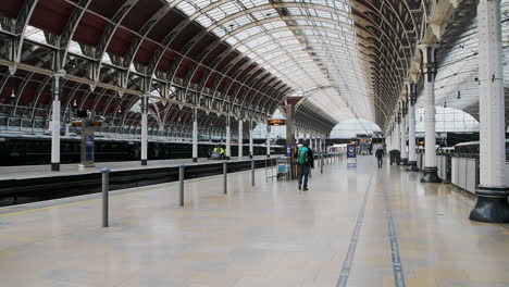 Una-Persona-Caminando-En-La-Estación-De-Tren-De-Paddington-Vacía-Durante-El-Cierre-Del-Coronavirus-Covid-19-En-Londres-Cuando-El-Transporte-Público-Estaba-Tranquilo-Y-Desierto-Sin-Gente-En-Inglaterra,-Europa