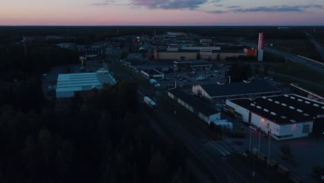 Vista-Aérea-Siguiendo-Camiones-En-Una-Zona-Industrial-En-Vaasa,-Anochecer-En-Finlandia---Reversa,-Disparo-Con-Drones