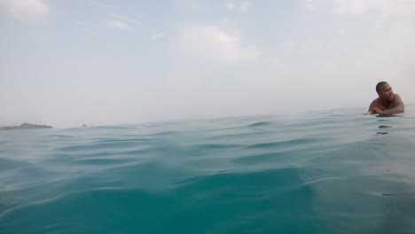 An-afro-American-man-is-floating-or-swimming-on-a-turquoise-deep-blue-ocean-near-an-island-close-to-Cartagena-de-Indias,-Colombia