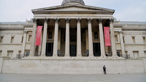 Quiet-and-empty-Central-London-in-Covid-19-Coronavirus-lockdown-with-one-person-walking-at-The-National-Gallery-at-Trafalgar-Square,-a-popular-tourist-attraction-in-England,-UK