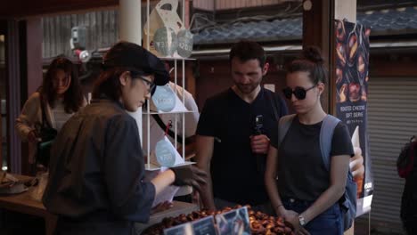 Turistas-Europeos-Comprando-Castañas-En-Kioto,-Japón.