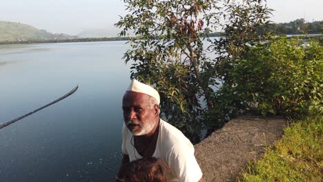 Abuelo-Con-Su-Nieto-Sentado-En-El-Suelo-Con-Un-Lago-Al-Fondo