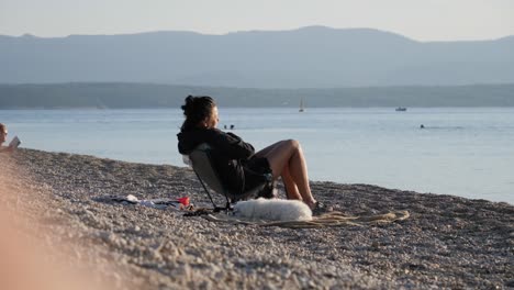 Mujer-Con-Perro-Blanco-Tomando-El-Sol-En-La-Playa