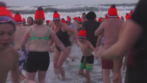 Gente-Celebrando-El-Tradicional-Nieuwjaarsduik-En-La-Playa-De-Texel-En-El-Norte-De-Holanda,-Países-Bajos---Toma-Estática-Media