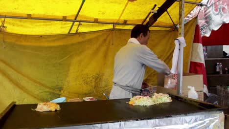 Local-japanese-man-explaining-how-to-make-hyroshima-okonomiyaki-at-the-kyoto-food-stalls